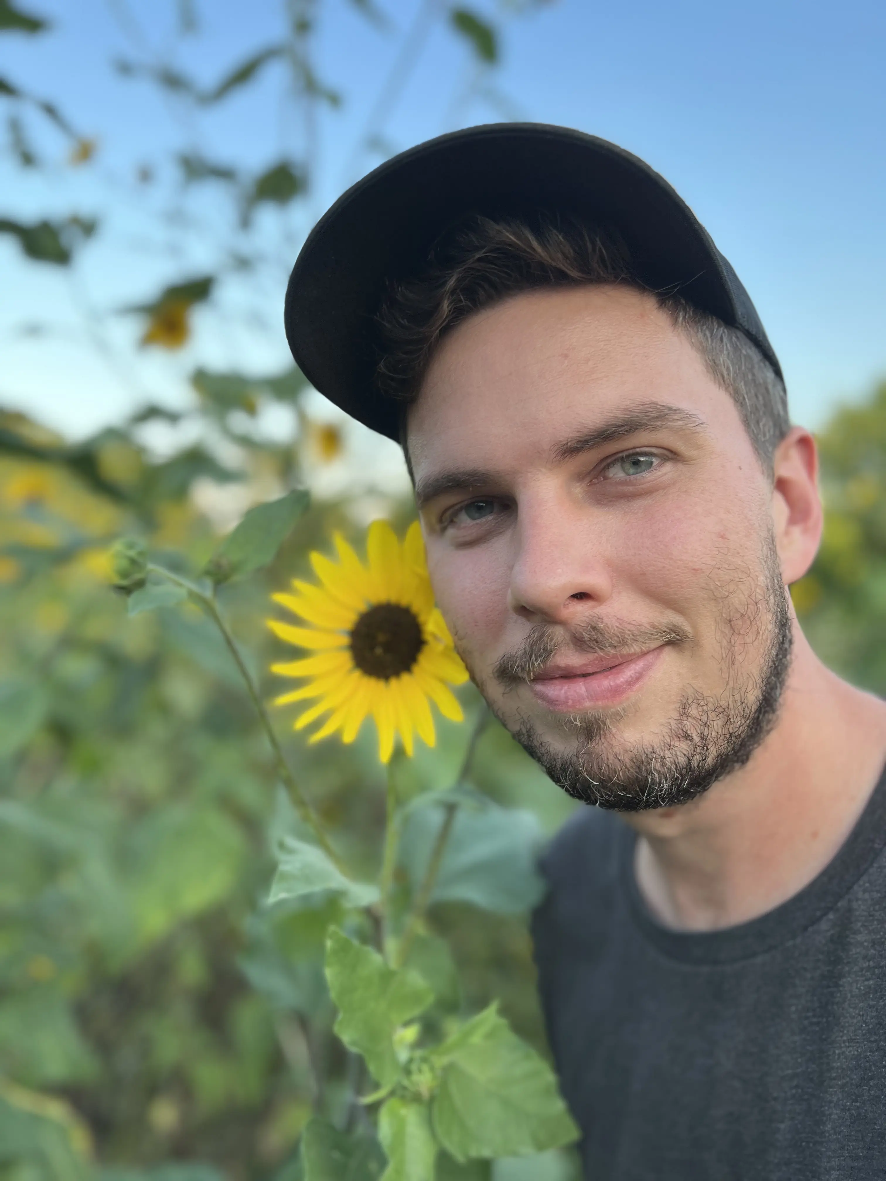 A handsom man standing next to a sunflower